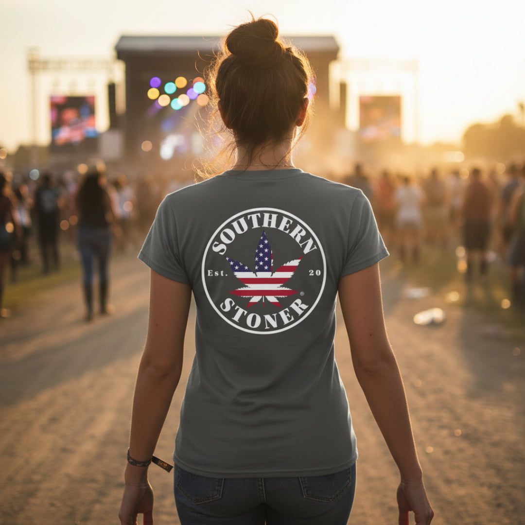 Woman wearing charcoal Southern Stoner® OG Women’s Tee at an outdoor concert, back view